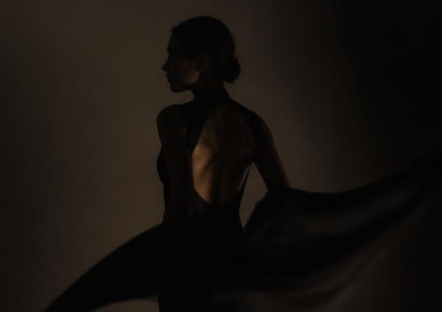 Film still of a woman in a dark gown turning in low light
